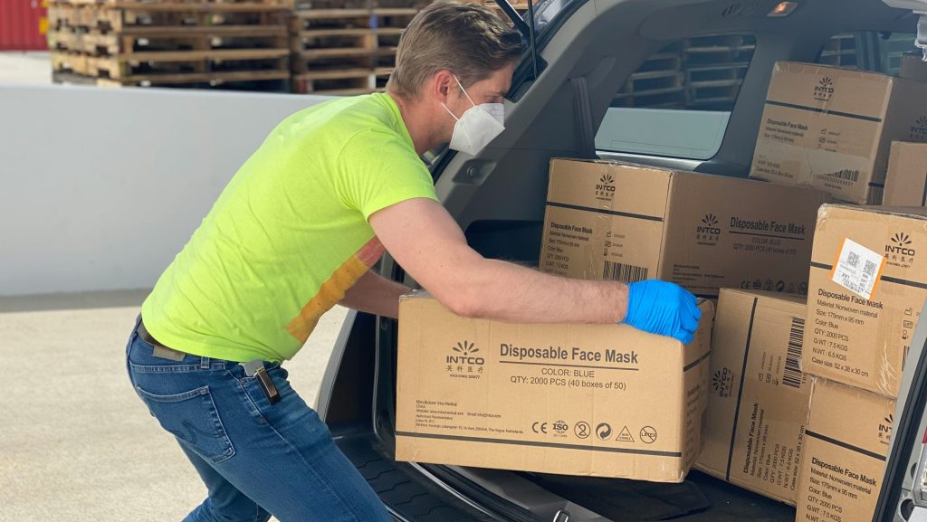 man in green t-shirt and blue denim jeans holding brown cardboard box